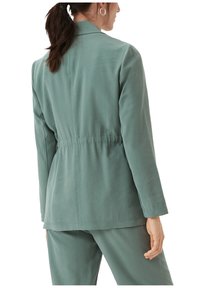 Lichtgroene blazer met een taille die is versmald, lange mouwen en een soepele textuur. Gemaakt in een getailleerd ontwerp met een kraag en een lichte draping aan de achterkant.