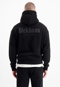 Zwarte hoodie met een voorzak, gemaakt van zachte stof. Bevat een donkergrijs logo op de achterkant, een ronde capuchon en geribbelde manchetten.