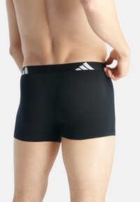 Boxer shorts negros confeccionados en una tela suave, que presentan un diseño de bajo talle y una cinturilla en contraste con detalle de tres rayas blancas.