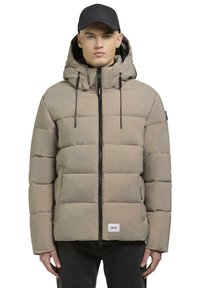 Beige puffjakke med hætte, der har en frontlynlås og justerbare snore. Glat tekstur og syede firkantede paneler.