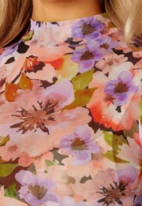 Blommigt mönstrat nätmaterial i rosa, lila och gröna nyanser med hög halsringning och mjukt, genomskinligt utseende.