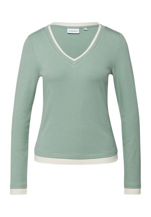 Długi rękaw, jasny zielony shirt z dekoltem w serek i białym obszyciem przy kołnierzu, mankietach i dolnym brzegu, o dopasowanym, casualowym stylu.