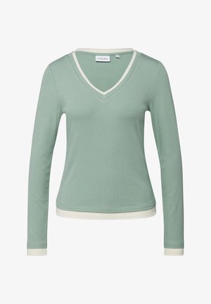 Długi rękaw, jasny zielony shirt z dekoltem w serek i białym obszyciem przy kołnierzu, mankietach i dolnym brzegu, o dopasowanym, casualowym stylu.