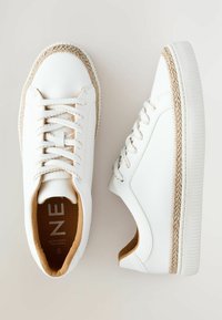 Sneakers bianchi in pelle sintetica, con un bordo in juta intrecciata attorno alla punta e rivestimento interno beige, dotati di lacci rotondi.