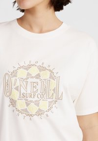 Vit bomullstshirt med en cirkulär grafisk design i beige och gult, med texten "O'Neill Surf Co." och "California."