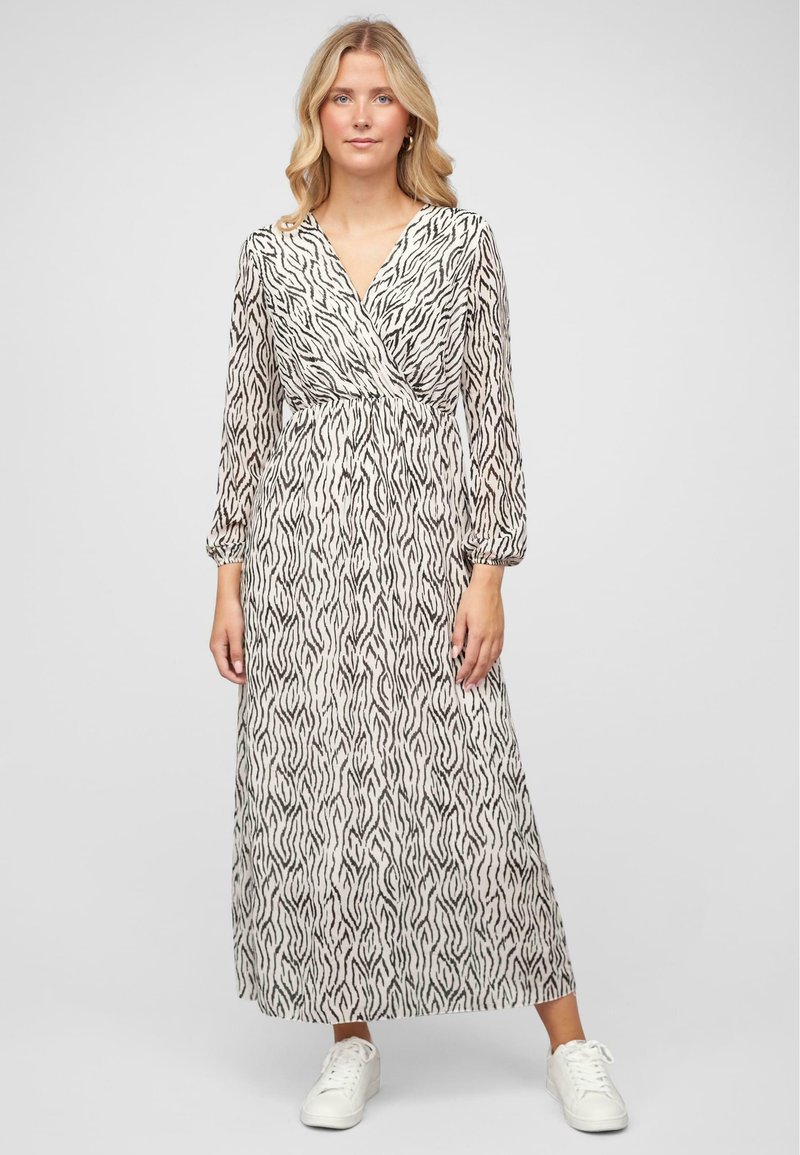 Robe maxi en tissu léger avec un motif de vagues noires sur fond crème, avec des manches longues et un design de corsage enveloppant.