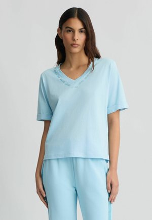 T-shirt di cotone azzurro chiaro con scollo a V, maniche corte e vestibilità comoda. Presenta un logo discreto attorno al collo.