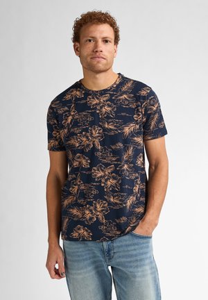 Marineblå t-shirt med blomstermønster i beige. Korte ærmer, rund halsudskæring og en afslappet pasform. Kombination med lyseblå jeans.