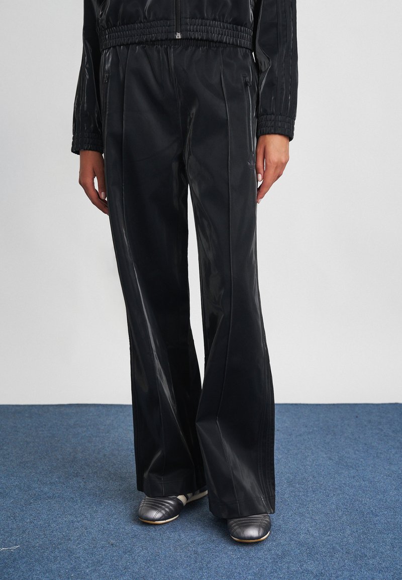 Μαύρο, γυαλιστερό, παντελόνι φαρδύς γραμμής από απαλό υλικό, με ελαστική μέση και διακριτική λεπτομέρεια επωνυμίας στο πλάι.