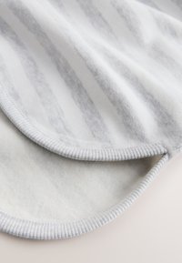 Pătură cu dungi gri și albe, cu o textură moale, margine zimțată și interior confortabil de fleece.