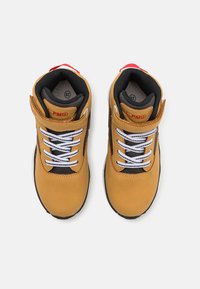 Sneaker in pelle marrone e tessuto nero con lacci bianchi, linguetta imbottita, dettaglio rosso sul tallone, punta arrotondata e suola in gomma. Taglia 28.
