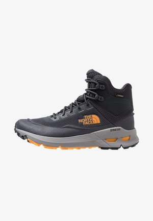 Scarpa da trekking alta nera e grigia con logo arancione, dettagli arancioni sulla suola e lacci neri, progettata per l'uso all'aperto.