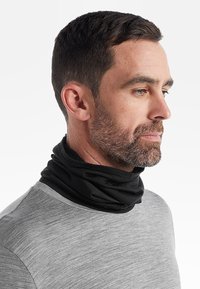 Svart halsduk gjord av mjukt, flexibelt tyg. Bärs runt halsen och kombineras med en ljusgrå skjorta. Slät textur, sömlös design.