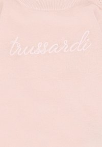Jasnoróżowy sweter dziany z haftowanym logo "trussardi" z przodu. Posiada okrągły dekolt i zapięcia na napy.