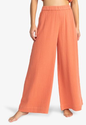 Pantalons larges en pêche, fabriqués dans un tissu texturé avec une taille élastique, présentant une coupe décontractée et de légères plis pour un look casual.