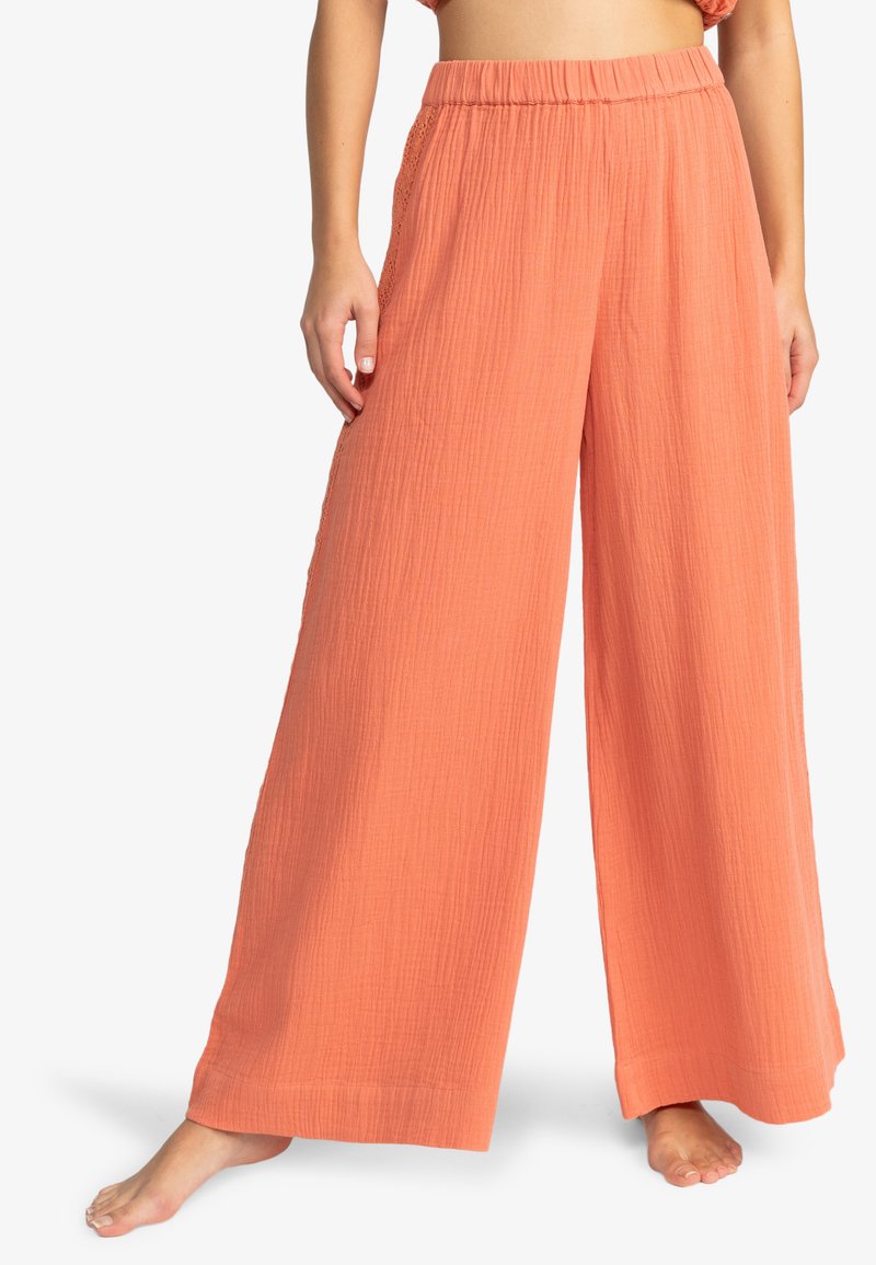 Pantalones de pierna ancha color durazno hechos de tejido texturizado con una cinturilla elástica, que cuentan con un ajuste holgado y arrugas sutiles para un aspecto casual.