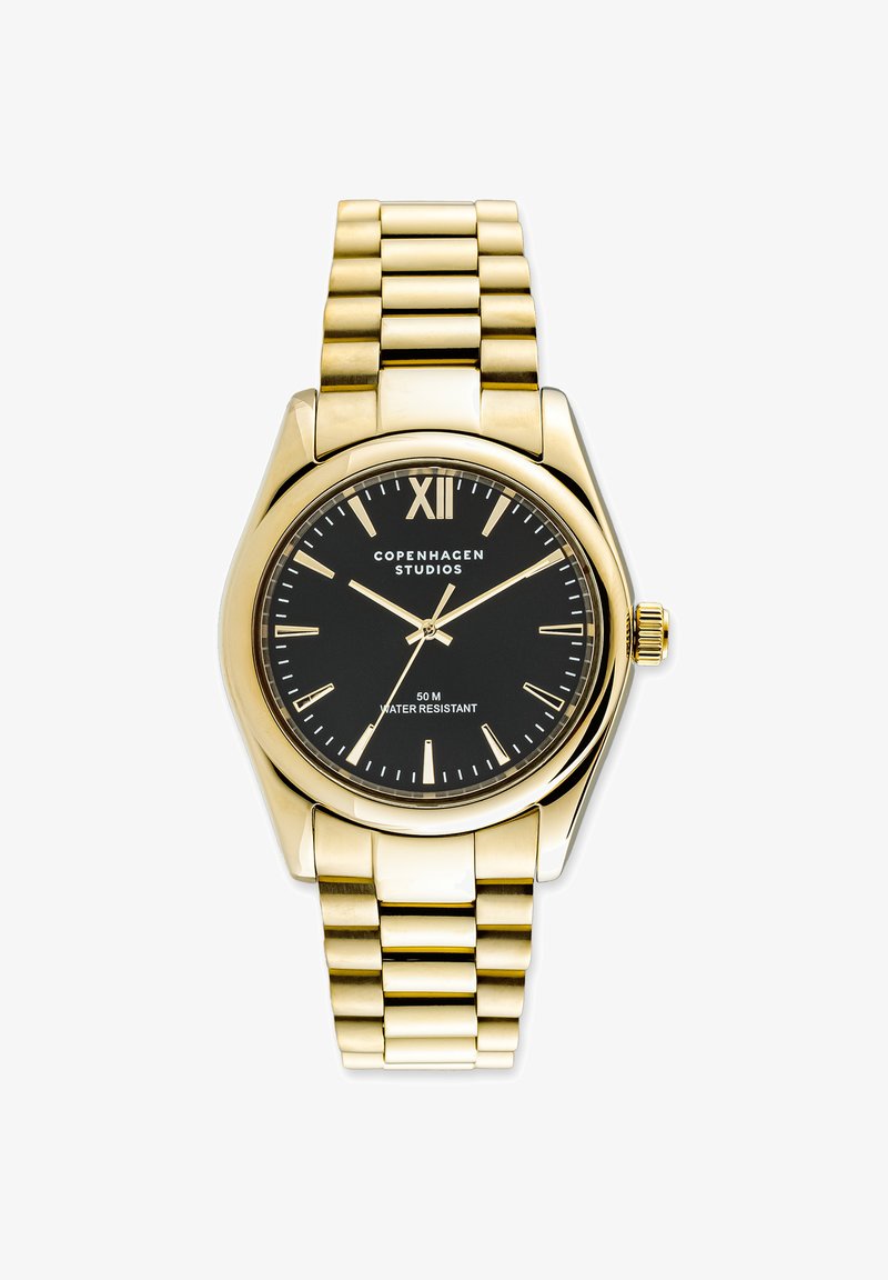 Goldene Metallarmbanduhr mit schwarzem Ziffernblatt, goldenen Stundenmarkierungen und "Copenhagen Studios"-Branding, die die Uhrzeit 10:10:09 anzeigt.