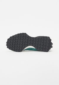 Suola di scarpa in gomma nera con grip testurizzato e motivi circolari. Accenti in materiale azzurro chiaro lungo il bordo e il sottopiede. Finitura liscia.