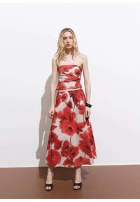 Ärmelloses Kleid mit tailliertem Oberteil und fließendem A-Linien-Rock. Verfügt über ein rotes Blumenmuster auf hellem Hintergrund. Glattes Material und knöchellang.