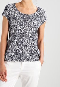 Blusa de rayas azul marino y blanca con mangas cortas y escote redondo, que presenta un diseño de paisley y un ajuste relajado.