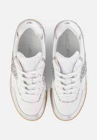 White sneakers with silver glitter accents, smooth leather upper, textured rubber sole, and round toe; features thick white laces.