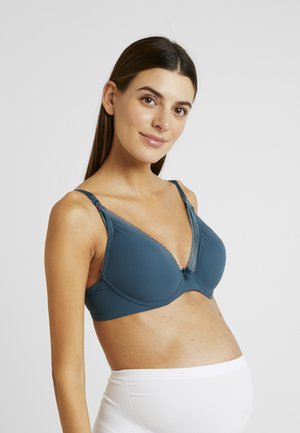 Soutien-gorge de maternité en teal, présentant un décolleté en V profond, une dentelle le long du bord supérieur, des bretelles réglables, et un tissu lisse pour le confort.