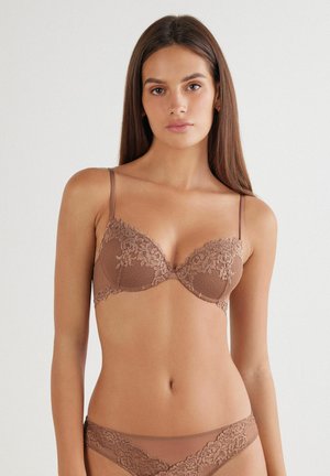 Bra in Brauntönen mit Spitzenbesatz, gepolsterten Cups und verstellbaren Trägern. Verfügt über einen strukturierten Oberflächeneffekt und einen floralen Spitzenakzent an den Kanten der Cups.