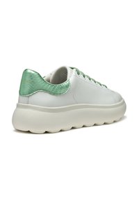 Baskets blanches avec un dessus en cuir lisse, un accent métallique vert au talon, des lacets texturés et une semelle en caoutchouc épaisse.
