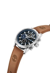 Hronogrāfa pulkstenis ar tumši zilu ciparnīcu, sudraba akcentiem un nerūsējošā tērauda korpusu. Aprīkots ar brūnu ādas siksnu ar iepresētu logotipu.