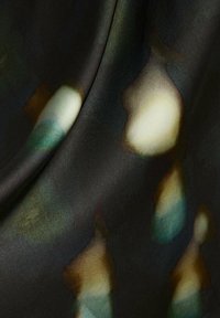 Dark fabric with soft, blurred patches of white, teal, and brown shades, creating an abstract, flowing pattern.