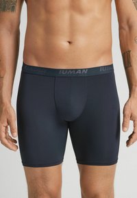 Mörkblå herrboxer i stretchigt och glatt tyg. Har en elastisk midja med varumärkeslogotyp och en figurnära design.