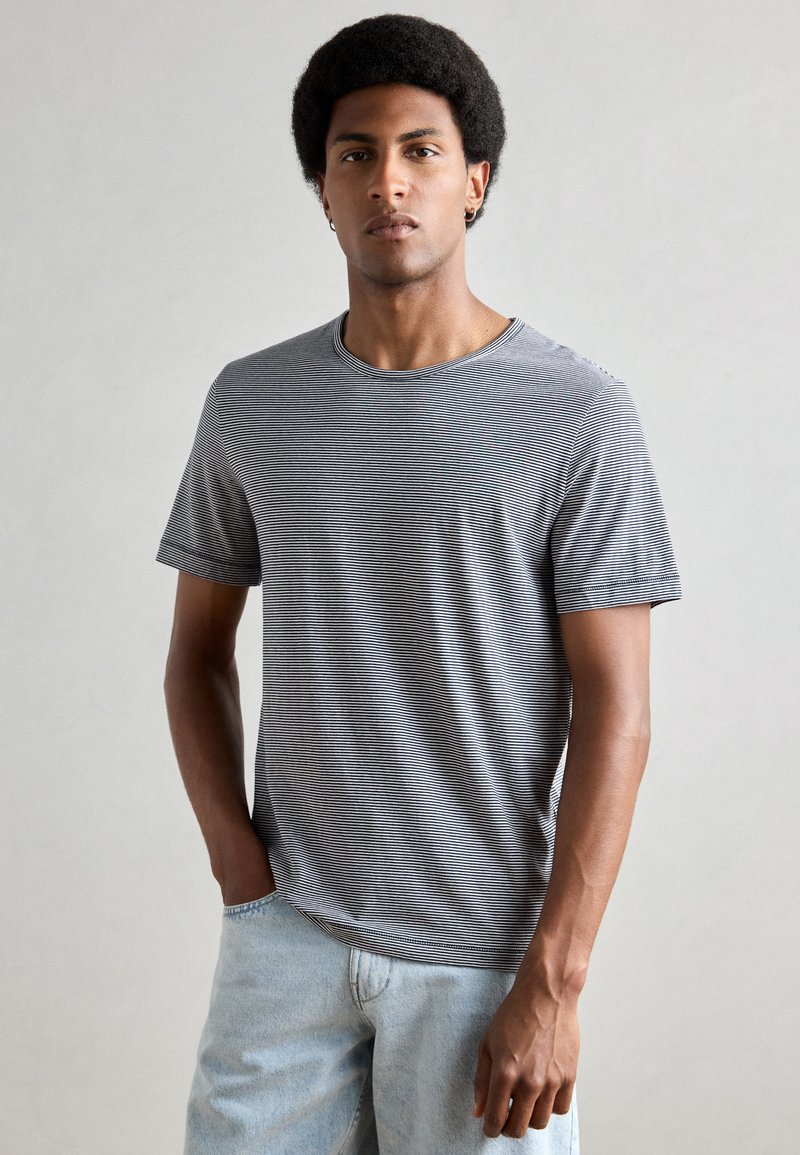 Grijze gestreepte t-shirt met een ronde hals en korte mouwen, gemaakt van zacht materiaal. Het heeft een relaxte pasvorm en een subtiele textuur.