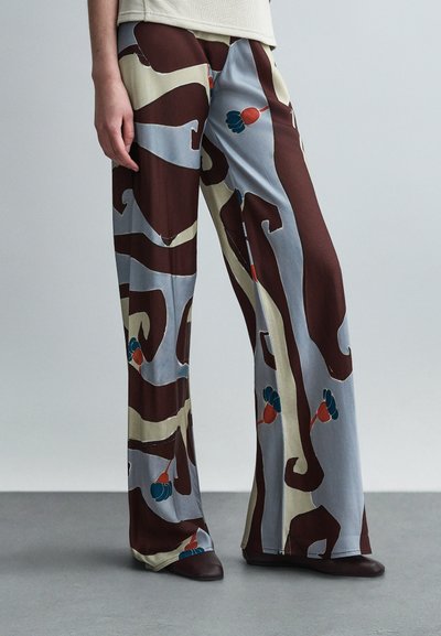 Hose mit weitem Bein aus glattem Stoff mit abstraktem Muster in Braun, Blau und Beige sowie floralen Akzenten.