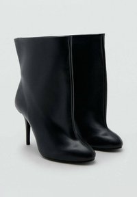 Črni gležnarji iz usnja s čistim dizajnom, z ostrim koncem in visokim peto z iglo. Gladek tekstura z minimalnimi šivi.