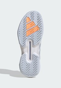 Podešev sportovní tenisky, která má šedou gumovou základnu se vzorem rybí kosti a oranžovými trojúhelníkovými akcenty pro lepší trakci.