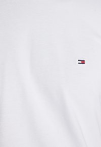 Hvid bomuld t-shirt med et lille broderet logo i marineblå og rød på venstre brystområde, med en glat tekstur og klassisk rund halsudskæring.