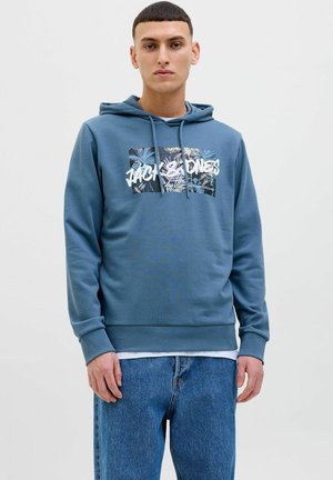 Sudadera de algodón azul con bolsillo canguro, capucha con cordón y un estampado gráfico que presenta elementos tropicales y texto en la parte delantera.