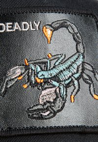 Black fabric patch featuring a detailed embroidered scorpion in teal and gray, with orange accents. Text above reads "DEADLY."