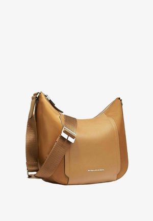 Borsa a tracolla in pelle color cuoio con un design morbido, dotata di una tracolla larga regolabile e dettagli in metallo argentato. Marchio minimalista visibile.