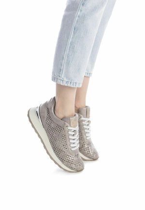 Zapatillas de ante gris perforadas con cordones blancos, suela acolchada y un acento reflectante. Usadas con vaqueros cortos de color azul claro.