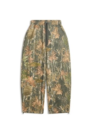 Pantalons camouflage avec une taille élastique, présentant un mélange de motifs de feuilles vertes, brunes et beiges. Accents zippés au niveau des chevilles.
