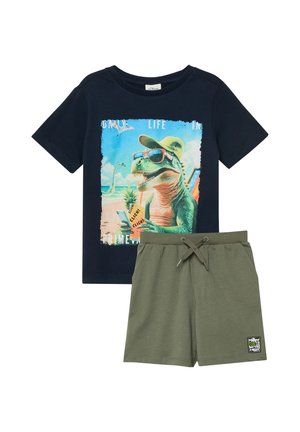 Granatowy t-shirt z dinozaurem noszącym okulary przeciwsłoneczne i kapelusz na plaży, zestawiony z oliwkowozielonymi szortami na sznurku.