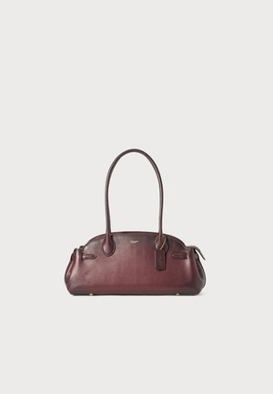Sac à main en cuir bordeaux à forme arrondie, avec deux poignées, poches latérales et quincaillerie en ton doré. Présente une étiquette suspendue avec le logo de la marque.