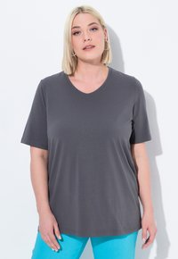 Grijze T-shirt met korte mouwen en V-hals in een zachte stof, met een relaxte pasvorm. Gekocht met lichtblauwe broeken. Kenmerken zijn onder andere een gladde textuur.