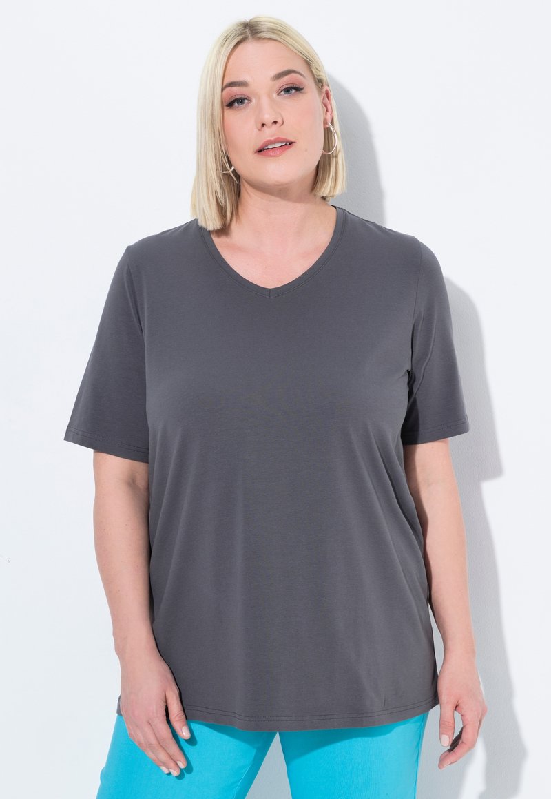 Grijze T-shirt met korte mouwen en V-hals in een zachte stof, met een relaxte pasvorm. Gekocht met lichtblauwe broeken. Kenmerken zijn onder andere een gladde textuur.