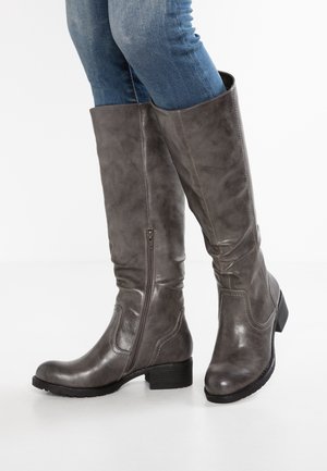 Grijze faux leren kniehoge laarzen met een zijrits, ronde neus en een middelhoog blokhak, gepresenteerd met blauwe jeans. Gladde textuur.