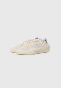 Beige Sportschuhe mit Mesh- und Wildlederelementen, runder Zehenpartie, Gummisohle und lila Fersenlasche. Verfügt über ein dezentes Logo an der Seite.