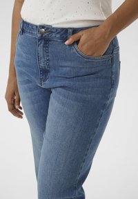 Blauwe hoge taille jeans met een gladde textuur, voorzien van een sluiting met een knop aan de voorkant, riemlussen en zijzakken.