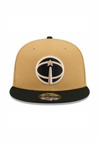 Casquette snapback beige avec une visière noire, arborant un logo circulaire prominent en noir et blanc avec une étoile. Confectionnée en tissu texturé.