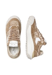 Baskets beiges présentant un mélange de matériaux en daim et en satin, une semelle à motifs texturés, ainsi que des accents de couleur claire sur le talon et le logo.
